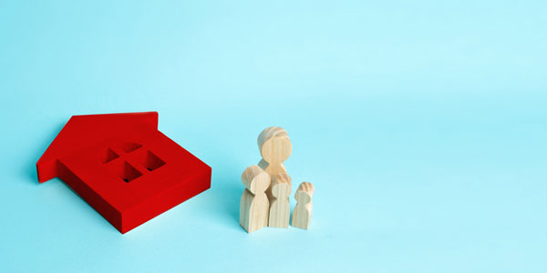 The Family Stands Near The Red Ruined Fallen House. Loss Of Housing, Home Insurance. Accident, Natural Disaster, War. Buying Immobility Homeless Family. People Stand Near The House.